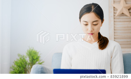 使用便攜式計算機的一個少婦在沙發 83921899