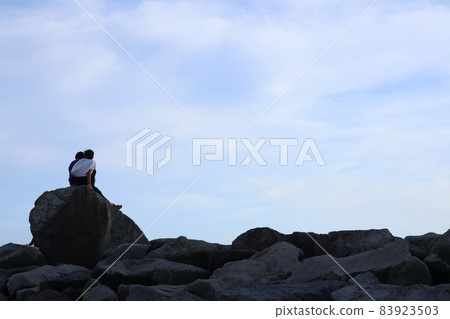 Image of youth and friendship between two people sitting on a big rock Image of youth and friendship between two people sitting on a big rock 83923503