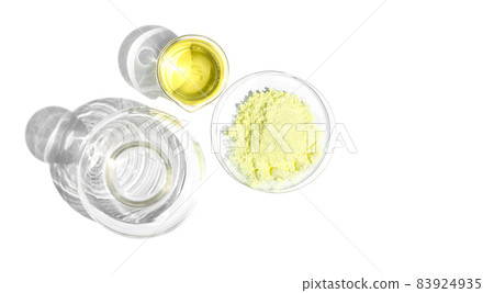 Cosmetic chemicals ingredient on white laboratory table. Sulfur Powder in Chemical Watch Glass and Poly Aluminium chloride liquid in beaker place next to Erlenmeyer flask. Top View 83924935