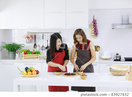 Happy ethnic housewives serving table with assorted tasty food for lunch in kitchen at home Happy ethnic housewives serving table with assorted tasty food for lunch in kitchen at home 83927832