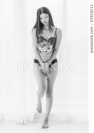 Beautiful young sexy girl on seductive underwear sadly standing alone with bunch of flower on her unsatisfied blue day 83928211