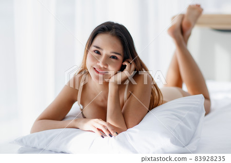 Beautiful young naughty Asian girl with sexy bra enjoy lie down with pillow on white bed and impassioned smile for bright morning of rest day. Beautiful young naughty Asian girl with sexy bra enjoy lie down with pillow on white bed and impassioned smile for bright morning of rest day. 83928235
