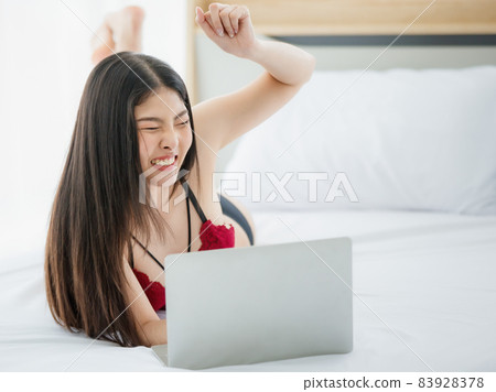 Beautiful young naughty sexy girl with long hair and romantic underwear lie down on bed end and enjoy funny working on laptop in bright morning of rest day Beautiful young naughty sexy girl with long hair and romantic underwear lie down on bed end and enjoy funny working on laptop in bright morning of rest day 83928378