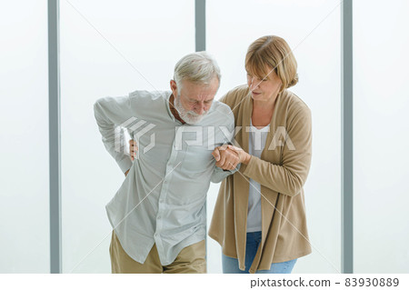 Caucasian old senior elderly supportive wife helping support holding hands of unhealthy sick grey bearded male husband walking when having emergency painful muscle and lower backache injury problem Caucasian old senior elderly supportive wife helping support holding hands of unhealthy sick grey bearded male husband walking when having emergency painful muscle and lower backache injury problem 83930889
