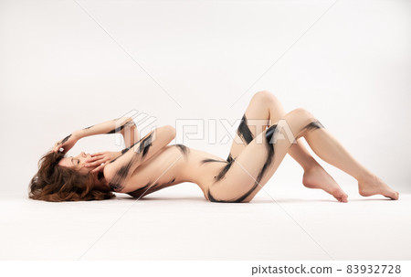 naked girl lying sexy on the floor painted with black paint on a white background naked girl lying sexy on the floor painted with black paint on a white background 83932728