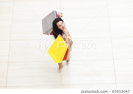 Happy woman with packages on floor of shopping mall Happy woman with packages on floor of shopping mall 83933047