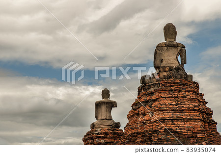 Ancient old buddha statue sculpture is damaged at the old temple in Ayuthaya province. Back side of Buddha statue on wall with blue sky background. 83935074