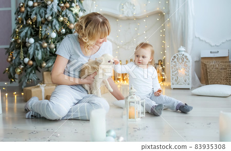 Family of two people mother and little girl at home on the background of a fireplace and a Christmas tree 83935308