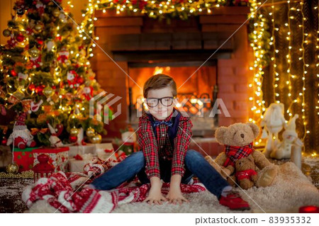 A boy dressed in a sweater against the backdrop of beautiful festive Christmas garlands A boy dressed in a sweater against the backdrop of beautiful festive Christmas garlands 83935332