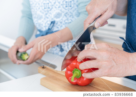 Up the hand of a middle-aged man who cuts paprika in the kitchen Up the hand of a middle-aged man who cuts paprika in the kitchen 83936668