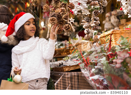 Portrait of joyful small girl in hat choosing Christmas toys 83940110