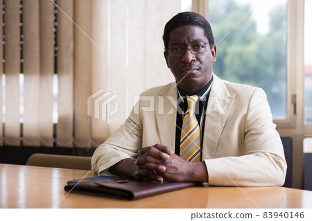 Confident businessman sitting with briefcase of documents in meeting room Confident businessman sitting with briefcase of documents in meeting room 83940146