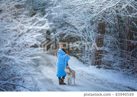 Woman winter is worth in the forest and holds dog on tight leash Woman winter is worth in the forest and holds dog on tight leash 83940589