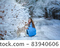 A dog walks in a snowy forest with a woman 83940606