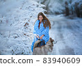 A dog walks in a snowy forest with a woman 83940609