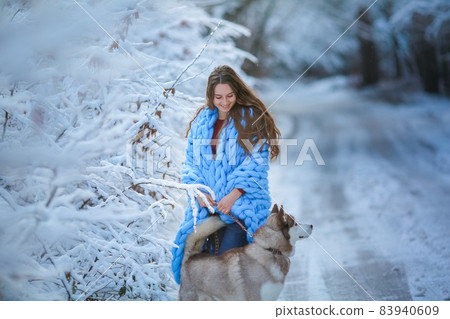 A dog walks in a snowy forest with a woman A dog walks in a snowy forest with a woman 83940609