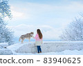 A woman with a husky dog walking on winter snow-covered mountains 83940625