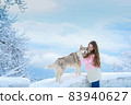 A woman with a husky dog walking on winter snow-covered mountains 83940627