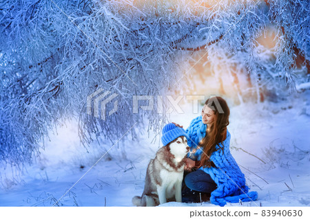 A woman with a husky dog walking on winter snow-covered mountains A woman with a husky dog walking on winter snow-covered mountains 83940630