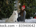 A young girl with a dog near the Christmas tree 83940642