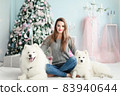 A young girl with a dog near the Christmas tree 83940644