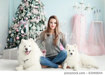 A young girl with a dog near the Christmas tree A young girl with a dog near the Christmas tree 83940644