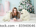 A young girl with a dog near the Christmas tree 83940646