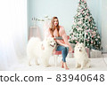A young girl with a dog near the Christmas tree 83940648