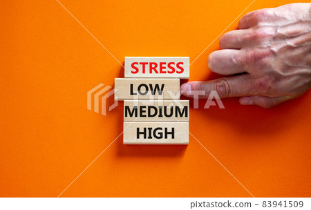 Low or high stress level symbol. Businessman chooses the wooden block with words low stress. Words stress low medium high. Beautiful orange background. Low or high stress level concept. Copy space. Low or high stress level symbol. Businessman chooses the wooden block with words low stress. Words stress low medium high. Beautiful orange background. Low or high stress level concept. Copy space. 83941509