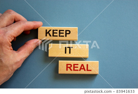 Male hand placing a block with word 'keep' on top of a blocks tower with words 'it real'. Beautiful blue background. Copy space. Business concept. 83941633