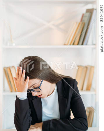 Overwork fatigue. Deadline anxiety. Workaholic lifestyle. Tired exhausted business woman suffering from stress headache at light office workplace interior. Overwork fatigue. Deadline anxiety. Workaholic lifestyle. Tired exhausted business woman suffering from stress headache at light office workplace interior. 83941672