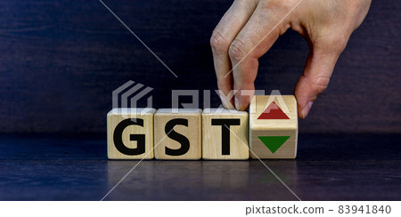 GST, goods and services tax symbol. Businessman holds a cube with up and down icon. Word 'GST'. Beautiful grey background. Copy space. Business and growth of GST, goods and services tax concept. GST, goods and services tax symbol. Businessman holds a cube with up and down icon. Word 'GST'. Beautiful grey background. Copy space. Business and growth of GST, goods and services tax concept. 83941840
