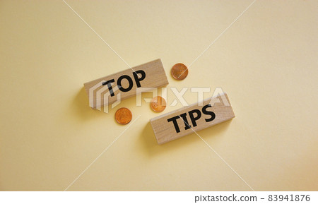 Top tips symbol. Concept words 'top tips' on wooden blocks on a beautiful white background, metallic coins. Business and top tips concept, copy space. Top tips symbol. Concept words 'top tips' on wooden blocks on a beautiful white background, metallic coins. Business and top tips concept, copy space. 83941876