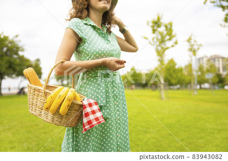 Young woman preparing to outdoor picnic at park in spring day 83943082