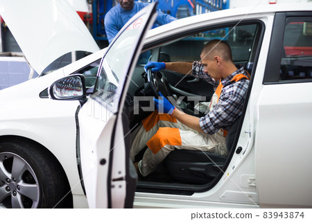 Serviceman making car diagnostics in a workshop Serviceman making car diagnostics in a workshop 83943874