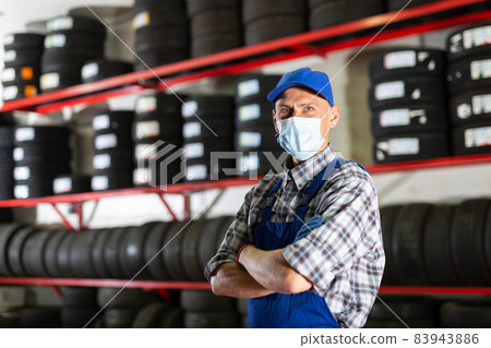 Auto mechanic in protective mask on background of car tires in tire service Auto mechanic in protective mask on background of car tires in tire service 83943886