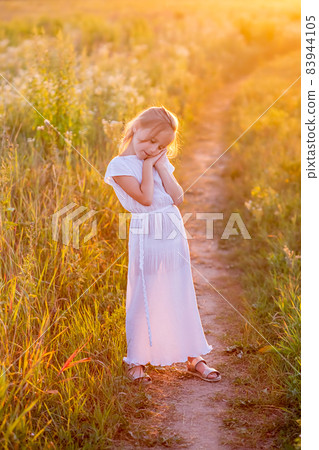 Cute little caucasian child girl in white dress posing looking at camera 83944105