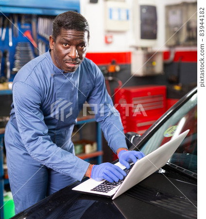 Mechanic using a laptop to work in service Mechanic using a laptop to work in service 83944182