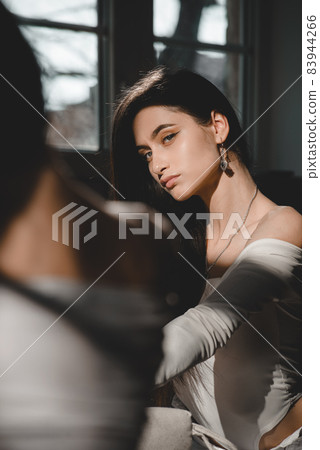 portrait of beautiful gentle woman in a white bodysuit posing in the sunshine. Black long hair. sensuality and tenderness portrait of beautiful gentle woman in a white bodysuit posing in the sunshine. Black long hair. sensuality and tenderness 83944266