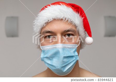 portrait man in Santa Claus hat and face mask 83944821