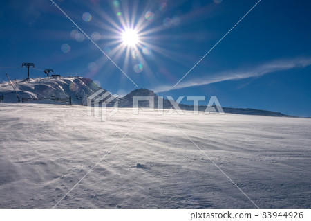 Bright Sun Over the Mountain Slope and Snowy Blizzard Bright Sun Over the Mountain Slope and Snowy Blizzard 83944926