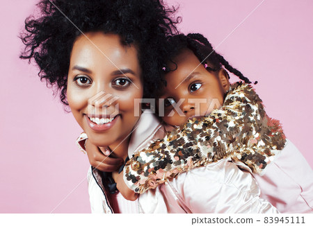 young pretty african-american mother with little cute daughter hugging, happy smiling on pink background, lifestyle modern people concept young pretty african-american mother with little cute daughter hugging, happy smiling on pink background, lifestyle modern people concept 83945111