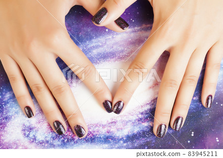 manicure stylish concept: woman fingers with nails purple glitter on nails like cosmos, universe background 83945211