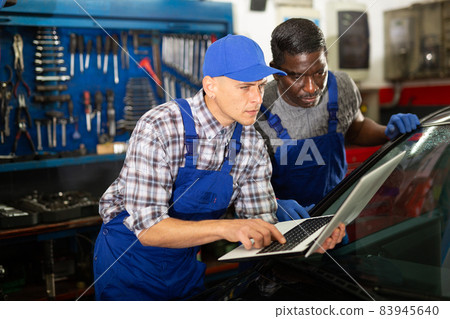 Two masters are replacing the filter in car on workplace Two masters are replacing the filter in car on workplace 83945640