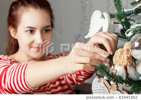 Young beautiful caucasian woman decorating Christmas tree. 83945802