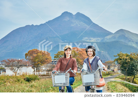 Young women and friends walking around Yufuin by bicycle 83946094