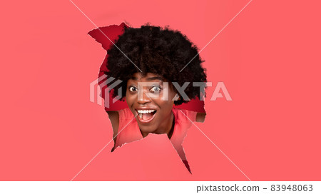 Surprised shocked black woman looking through paper hole 83948063