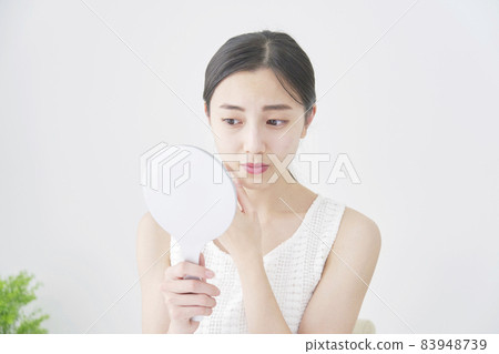 Cosmetology woman looking in the mirror worried 83948739