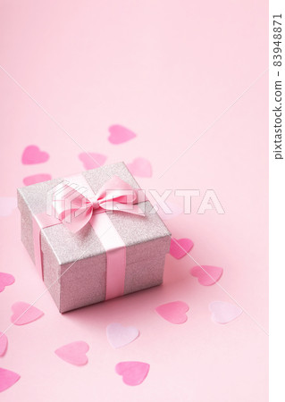 Silver glitter gift box with pink ribbon bow on pink background with confetti. 83948871