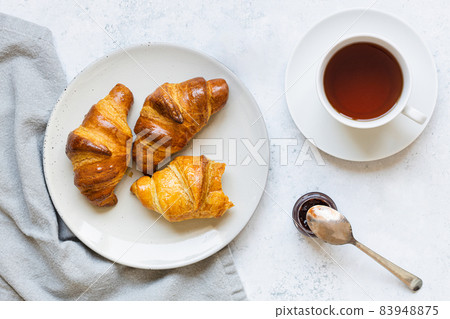 Breakfast scene. Croissants on plate and cup of tea. 83948875